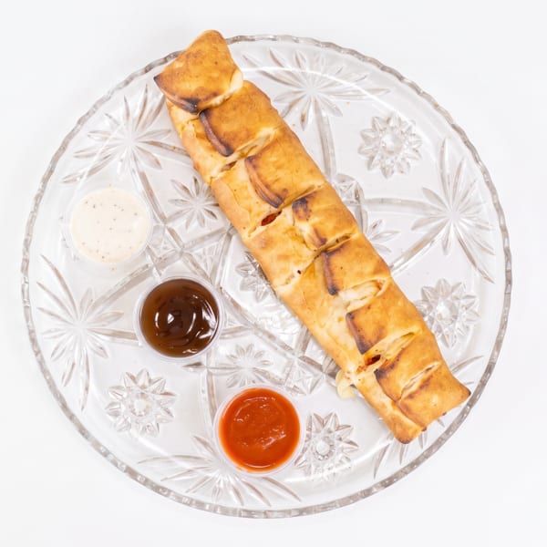 A golden-brown calzone with three dipping sauces on a clear glass plate.